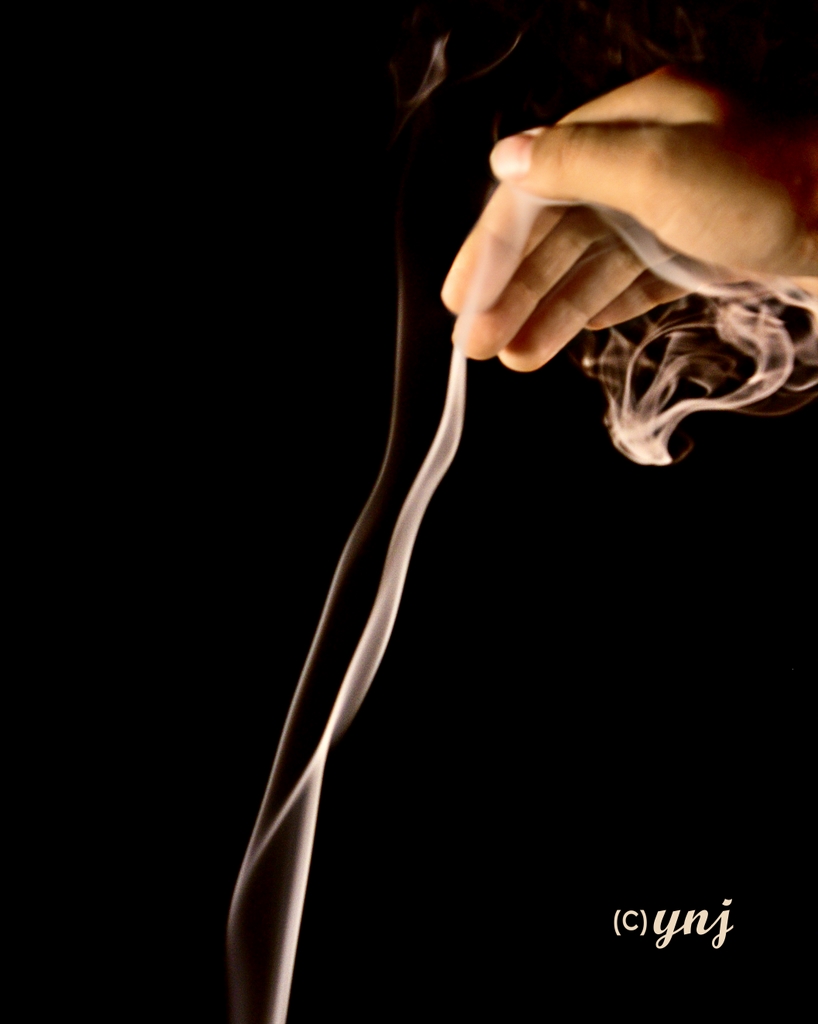 Hand holding a lit cigar with rising smoke